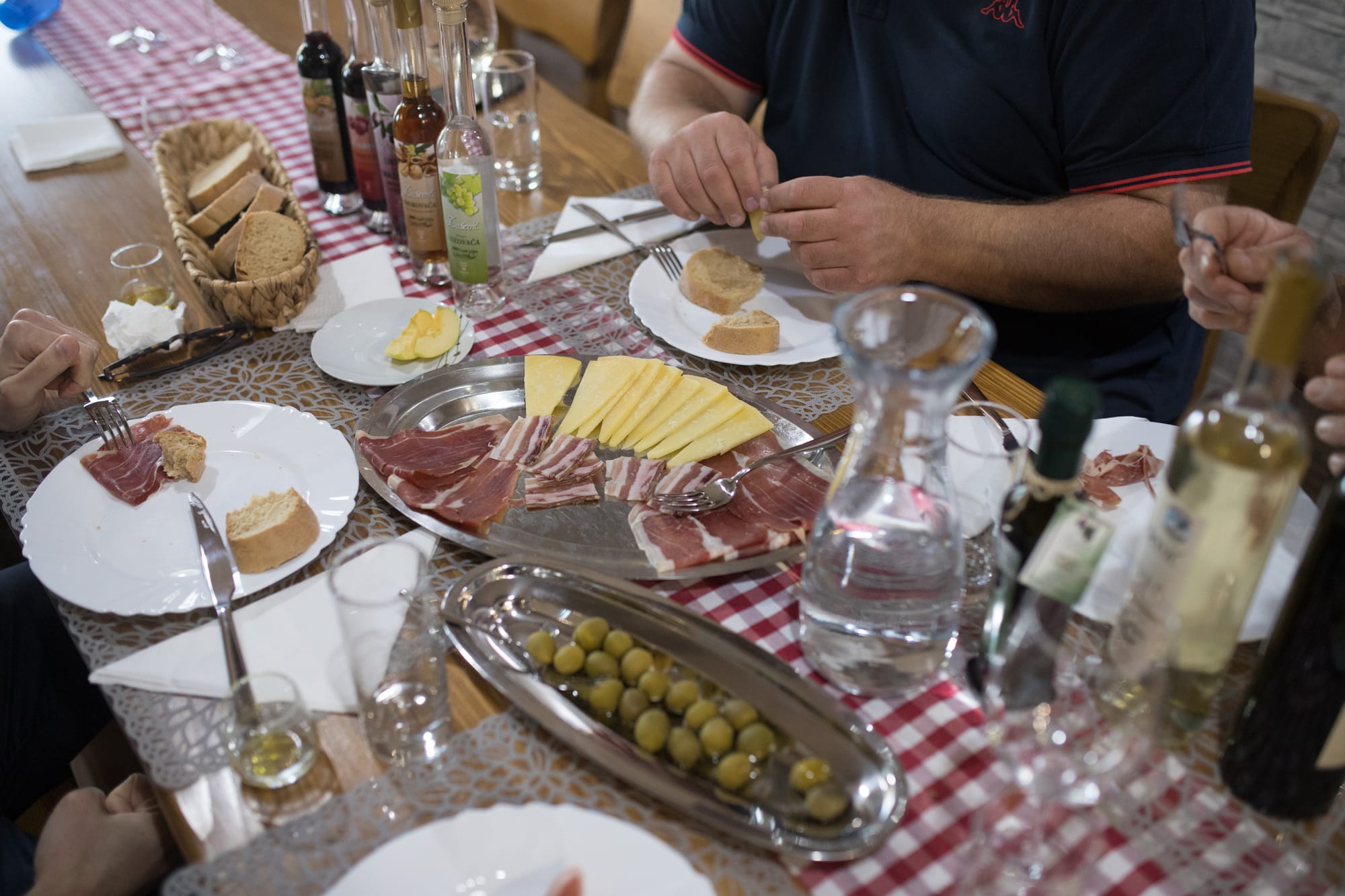 Prosciutto, cheese, olives, olive oil, wine and liqueurs on the table - on Dušević family farm near Zadar