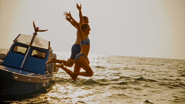 Couple jumping into the sea from the boat in Croatia.